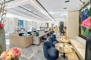 Descubra la elegancia atemporal del moderno lobby del Hotel The One Barcelona GL, donde las sillas azules y las mesas de mármol contrastan sorprendentemente con las vibrantes decoraciones florales en un entorno luminoso y espacioso. - ForTwo - Planes para parejas