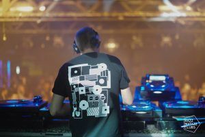 En Razzmatazz Barcelona, un DJ con auriculares pincha canciones mientras la animada multitud baila bajo luces de colores, creando una atmósfera de pura energía. - ForTwo - Planes para parejas