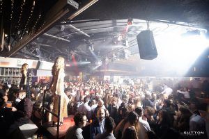 Sutton Club Barcelona rebosa de energía mientras luces vibrantes iluminan a los bailarines y socializadores, resaltando a dos mujeres en plataformas en la animada discoteca. - ForTwo - Planes para parejas