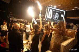 En el vibrante club Sutton de Barcelona, los asistentes celebran con bengalas, un gran juego de cartas y mujeres elegantemente vestidas, lo que realza el ambiente festivo. - ForTwo - Planes para parejas