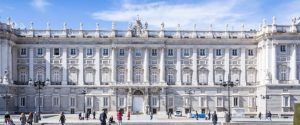 Los visitantes disfrutan de una Visita al Palacio Real de Madrid mientras pasean por la gran fachada bajo un cielo parcialmente nublado. - ForTwo - Planes para parejas