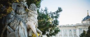 El histórico Palacio Real de Madrid cuenta con una estatua de un hombre a caballo debajo de un árbol, contra el cielo despejado: una vista esencial cuando exploras con Visita el Palacio Real de Madrid. - ForTwo - Planes para parejas