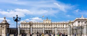 El majestuoso Palacio Real de Madrid se alza contra un cielo azul claro, atrayendo a innumerables turistas deseosos de vivir una experiencia memorable con "Visita el Palacio Real de Madrid. - ForTwo - Planes para parejas