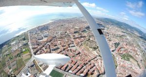 Experimente una vista aérea en un "Vuelo de iniciación en avióneta por Montserrat (Barcelona)" destacando los edificios, las carreteras y el océano de una ciudad costera. - ForTwo - Planes para parejas