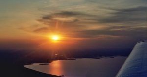 Disfrute de una impresionante vista del atardecer desde un vuelo de iniciación en avión por Montserrat (Barcelona), donde el cielo brilla sobre Montserrat y el lago de abajo brilla con reflejos. - ForTwo - Planes para parejas