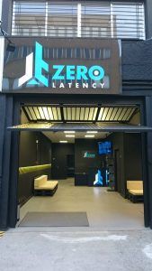 La tienda Zerolatency Terrassa tiene un elegante exterior negro con puertas de garaje abiertas, que dan la bienvenida a los entusiastas de la realidad virtual a un espacio minimalista diseñado para experiencias multijugador. - ForTwo - Planes para parejas