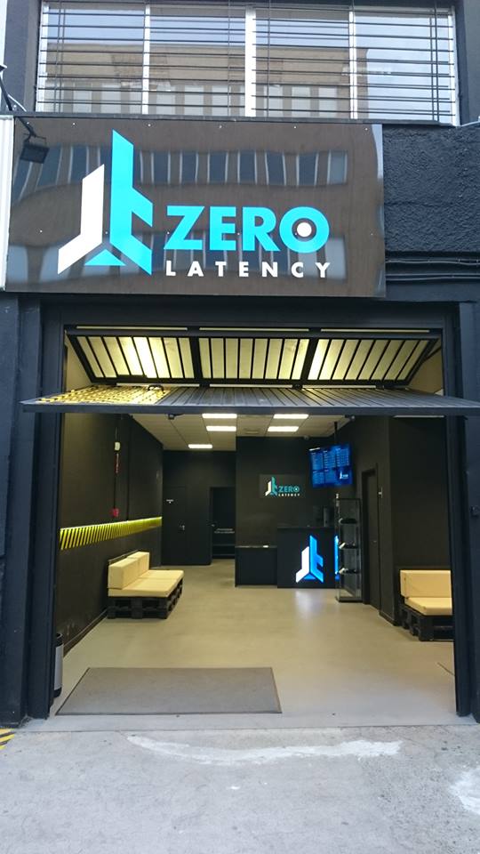 La tienda Zerolatency Terrassa tiene un elegante exterior negro con puertas de garaje abiertas, que dan la bienvenida a los entusiastas de la realidad virtual a un espacio minimalista diseñado para experiencias multijugador. - ForTwo - Planes para parejas