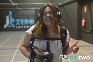 En la arena Zerolatency VR, una persona sonríe con el pulgar hacia arriba, equipada con equipo y casco, mientras el logotipo de Zero Latency brilla detrás de ella, encapsulando la esencia emocionante de la Experiencia de realidad virtual multijugador Zerolatency en Terrassa. - ForTwo - Planes para parejas