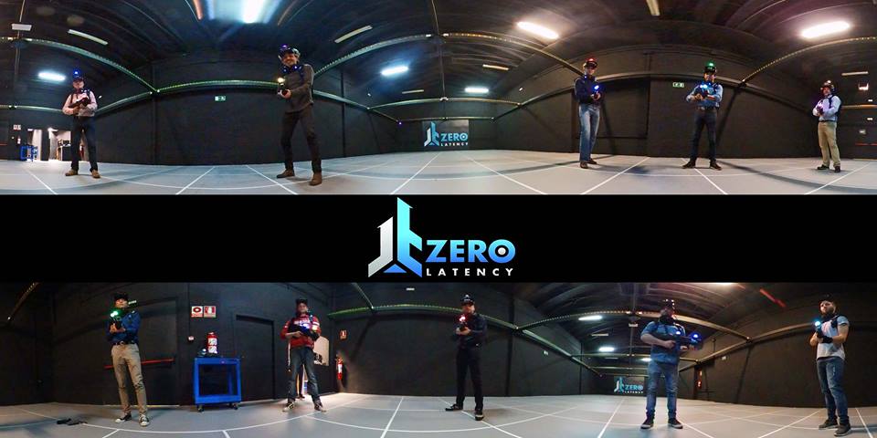 Los gamers, inmersos en la Experiencia de Realidad Virtual Multijugador Zerolatency (Terrassa), calzan equipos VR y dominan la arena con el logo de Zerolatency en el centro. - ForTwo - Planes para parejas