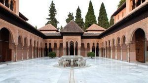 Descubra el cautivador patio de la Alhambra de Granada con nuestra "Visita guiada a la Alhambra con entrada incluida". Maravíllese con la fuente central, las majestuosas estatuas de leones y los frondosos árboles. Explore los ornamentados arcos que exhiben la belleza atemporal de esta joya histórica. - ForTwo - Planes para parejas