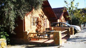 Disfrute del Bungalow con jacuzzi privado y cena a los pies de Sierra Nevada (Granada), que cuenta con un pequeño patio con mesa y sillas junto a su coche aparcado bajo los árboles en un día soleado, todo ello preparado para la máxima relajación. - ForTwo - Planes para parejas