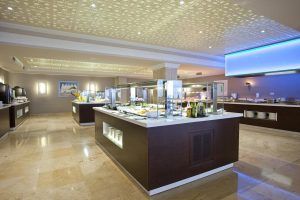 El moderno restaurante del Hotel Torre del Mar (Ibiza) presenta exquisitas presentaciones de comida, suelos de mármol y un techo decorativo, encapsulando la esencia vibrante de Ibiza. - ForTwo - Planes para parejas