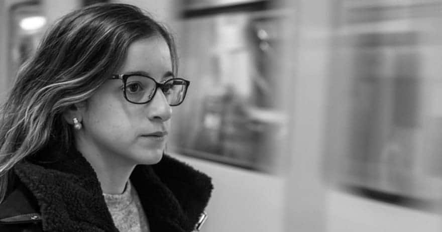 En la "Sesión de fotografía romántica outdoor (Barcelona)", una imagen en blanco y negro retrata a una mujer con gafas mirando un tren que pasa en una estación al aire libre, evocando una nostalgia romántica similar al encanto atemporal de Barcelona. - ForTwo - Planes para parejas