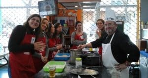En Madrid, la gente con delantal disfruta del Curso de preparación de hamburguesas premium, mientras un chef revuelve el caldero con maestría. Sonríen en la cocina, deseosos de dominar la elaboración de hamburguesas. - ForTwo - Planes para parejas