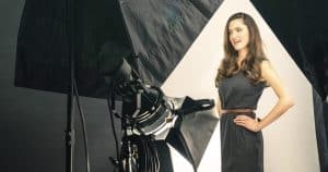 Durante una "Sesión de fotografía de pareja de estudio (Madrid)", una mujer posa con confianza bajo luces brillantes sobre un fondo blanco inmaculado, encarnando la elegancia. - ForTwo - Planes para parejas