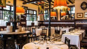 El Restaurante 7 Portes de Barcelona luce mesas redondas, manteles blancos, lámparas naranjas y grandes ventanales. - ForTwo - Planes para parejas