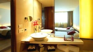 Disfrute de una moderna habitación en SB Diagonal Zero, Barcelona, con un elegante baño con lavabo sobre encimera y espejo iluminado. Relájese en la cómoda cama doble y comience el día con un desayuno con cava incluido en su experiencia Noche Deluxe. - ForTwo - Planes para parejas