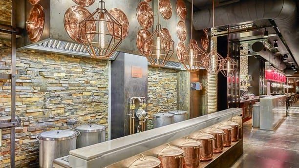 Una cocina moderna con ollas de cobre, lámparas geométricas y salpicadero de piedra evoca el estilo chic de Barcelona. El diseño industrial evoca la vibrante energía de la Pulpería Can Lampazas Para-lel (Barcelona). - ForTwo - Planes para parejas