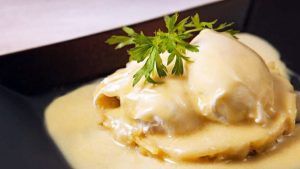 En el Restaurante Milo Grill de Barcelona, los raviolis se sirven en un plato negro, cubiertos con salsa cremosa y adornados con perejil fresco. - ForTwo - Planes para parejas