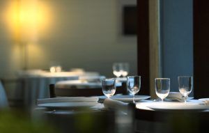 El elegante ambiente del restaurante del Hotel Atrio de Cáceres se caracteriza por una disposición impecable de las mesas, las copas y una iluminación cálida que crea un ambiente acogedor. - ForTwo - Planes para parejas