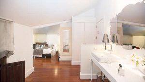 Un luminoso dormitorio en el ático con una cómoda cama, piso de madera y un moderno tocador bajo un techo inclinado ofrece un lujo similar a una Escapada de lujo en el hotel Palacio de los Patos con spa incluido (Granada). - ForTwo - Planes para parejas