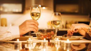 Bajo la luz de las velas, dos personas brindan con copas de vino sobre una ensalada, disfrutando de una velada tranquila que refleja el lujo del Escapada Hospes Palacio de Arenales + desayuno + masaje + spa (Cáceres), ideal para continuar la relajación con un masaje o una experiencia de spa. - ForTwo - Planes para parejas