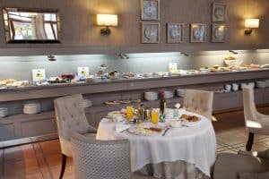 Un elegante desayuno buffet en el Restaurante Torreorgaz Parador de Cáceres, con mesa redonda para dos con bollería, zumo y una decoración elegante en el corazón de Cáceres. - ForTwo - Planes para parejas