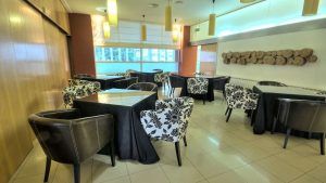 Un moderno restaurante con manteles negros, sillas florales, detalles de madera en las paredes y grandes ventanales se encuentra dentro de Escapada en el Hotel Sinagoga con desayuno, bombones y spa (Hervás). - ForTwo - Planes para parejas