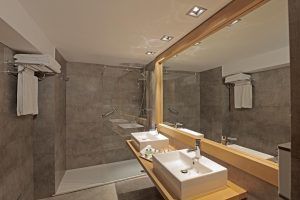 El Hotel NH Collection Palacio de Oquendo cuenta con un moderno baño con lavabos dobles, un gran espejo y una amplia ducha. Los huéspedes adoran los elegantes azulejos grises y las toallas cuidadosamente dobladas que completan su sofisticado ambiente. - ForTwo - Planes para parejas