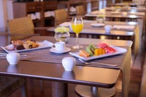 Bollería, fruta en rodajas, café y zumo de naranja se sirven elegantemente en el desayuno del acogedor Hotel NH Collection Palacio de Oquendo de Cáceres. - ForTwo - Planes para parejas