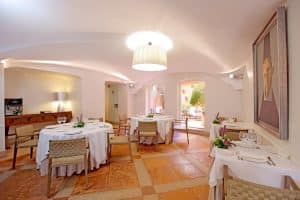 El elegante Hotel NH Collection Palacio de Oquendo en Cáceres ofrece un restaurante con mesas ordenadas, manteles blancos, iluminación cálida y una encantadora vista al patio con jardín. - ForTwo - Planes para parejas