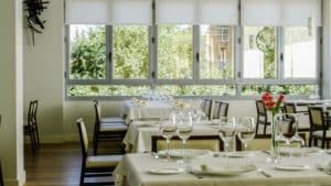 Restaurante Eustaquio Blanco (Cáceres) ofrece un ambiente gastronómico vibrante con sus mesas impecablemente dispuestas, manteles blancos y amplios ventanales que ofrecen vistas a la exuberante vegetación de Cáceres. - ForTwo - Planes para parejas