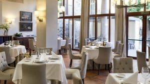 El Restaurante Torreorgaz Parador de Cáceres es un lugar luminoso y elegante en Torreorgaz, que cuenta con manteles blancos, sillas acolchadas, grandes ventanales y arte mural enmarcado. - ForTwo - Planes para parejas
