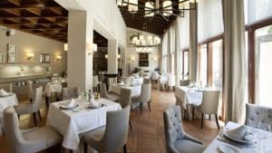 El Restaurante Torreorgaz Parador de Cáceres ofrece un ambiente elegante en el corazón de Cáceres, con manteles blancos, sillas con cojines, amplios ventanales y lámparas de araña. Ofrece un ambiente luminoso y acogedor, ideal para descubrir el encanto de Torreorgaz. - ForTwo - Planes para parejas