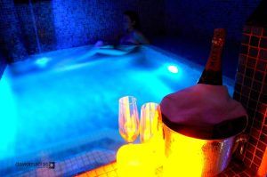 Disfrutando de un resplandor azul, uno se relaja en un tranquilo jacuzzi, que recuerda la sensación de un antiguo baño árabe. Copas de champán brillan cerca y ofrecen una escapada de lujo en Almazara de San Pedro - Casa rural en Sierra de Gata con baño árabe (Cáceres). - ForTwo - Planes para parejas