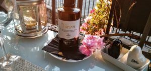 Una encantadora mesa con un toque rústico incluye un farol, una botella de aceite de oliva, flores rosas y saleros de Sr. y Sra., evocando el acogedor encanto de Almazara de San Pedro - Casa rural en Sierra de Gata con baño árabe (Cáceres). - ForTwo - Planes para parejas
