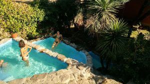 En Almazara de San Pedro, casa rural en Sierra de Gata con baño árabe (Cáceres), dos personas se relajan en una acogedora piscina rodeada de piedra en medio de una exuberante vegetación. - ForTwo - Planes para parejas