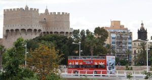 Las entradas para el autobús turístico de Valencia llevan a los turistas a través de torres y edificios históricos, con frondosos árboles y un cielo nublado que proporciona una vista pintoresca del encanto de la ciudad. - ForTwo - Planes para parejas