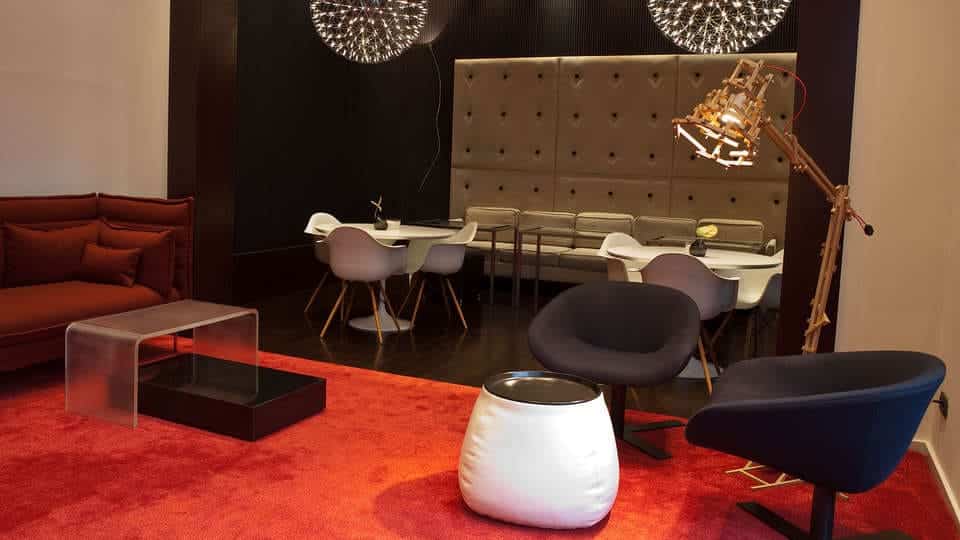 El Escapada Hotel SixtyTwo de Barcelona cuenta con un moderno salón con alfombra roja y elegantes sillas, un comedor con paredes de capitoné, lámparas colgantes esféricas y una exquisita selección de cava para mejorar su visita. - ForTwo - Planes para parejas