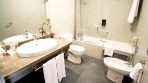 El baño cuenta con un gran espejo, lavabo, inodoro y un elegante bidé. Una lujosa bañera de hidromasaje invita a la relajación con un estilo que recuerda a la "Escapada con desayuno y entradas al Gran Casino Aljarafe" (Sevilla). Las toallas están cuidadosamente colgadas en un perchero para su comodidad. - ForTwo - Planes para parejas