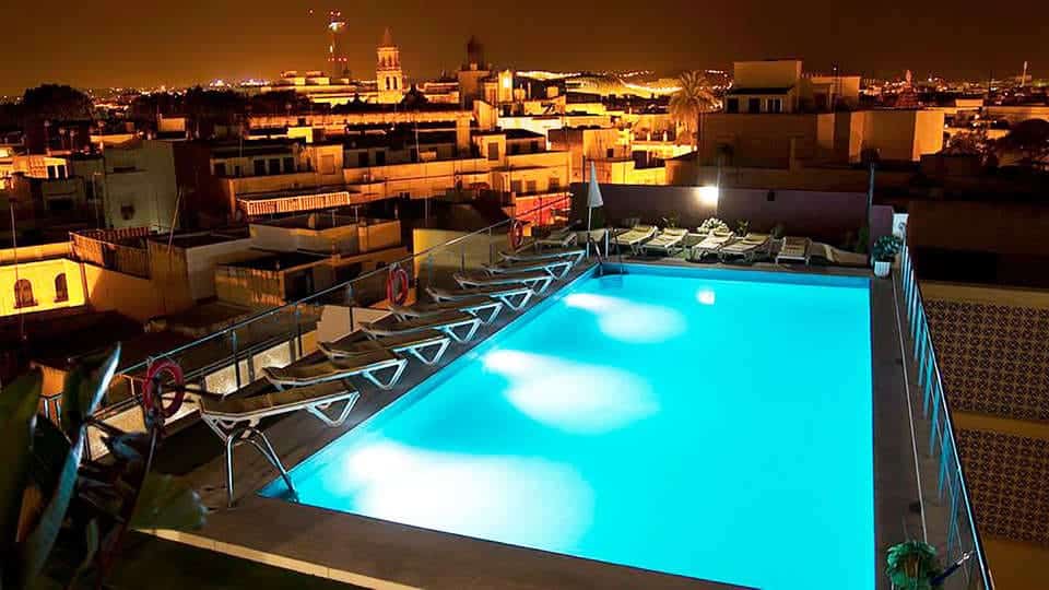 Disfrute de una piscina en la azotea iluminada por la noche con tumbonas para disfrutar de las vistas de la ciudad, ideal para tomar un cóctel con la "Escapada con piscina, cóctel y visita guiada (Sevilla). - ForTwo - Planes para parejas