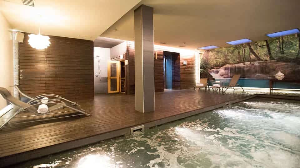 Experimente la tranquilidad en Escapada Hospes Palau de la Mar con desayuno y spa en Valencia, con un relajante jacuzzi, acogedoras tumbonas en una terraza de madera y una apacible sauna. El papel pintado con motivos naturales invita a la relajación: un refugio perfecto antes del desayuno. - ForTwo - Planes para parejas