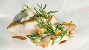 Plato gourmet: Disfruta de un filete de pescado al estilo valenciano con hierbas, salsa blanca y champiñones en el Restaurante Ampar-Palau de la Mar (Valencia), servido en un impecable plato blanco. - ForTwo - Planes para parejas