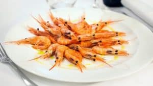 Un plato de camarones cocidos, perfectamente dispuesto y aderezado con especias aromáticas, realza la elegante mesa blanca de La Bodeguita de María (Valencia), infundiendo su experiencia gastronómica con el encanto culinario de Valencia. - ForTwo - Planes para parejas