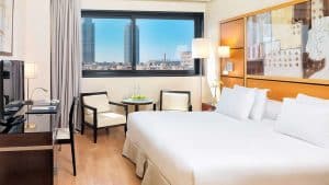 Disfrute de una escapada en el Hotel H10 Marina 4*, donde su habitación ofrece una cama grande, escritorio, TV, sillas y mesa. Contemple el paisaje urbano a través de amplios ventanales y relájese en el lujoso spa. Incluye desayuno, cava y fruta para una estancia inolvidable en Barcelona. - ForTwo - Planes para parejas