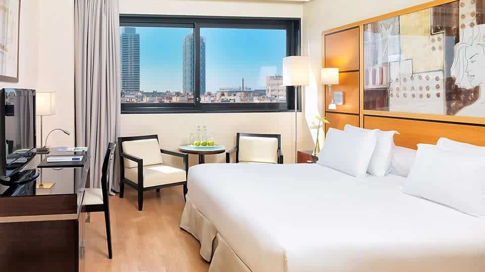 Disfrute de una escapada en el Hotel H10 Marina 4*, donde su habitación ofrece una cama grande, escritorio, TV, sillas y mesa. Contemple el paisaje urbano a través de amplios ventanales y relájese en el lujoso spa. Incluye desayuno, cava y fruta para una estancia inolvidable en Barcelona. - ForTwo - Planes para parejas