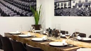 En La Bodeguita de María de Valencia, una mesa de comedor con platos y copas de vino realza la elegante decoración, enmarcada por fotografías en blanco y negro en las paredes. - ForTwo - Planes para parejas