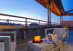 Al atardecer, relájese en la terraza del Hotel Silken Puerta de Valencia. Disfrute de cómodos asientos, un ambiente a la luz de las velas y una copa de champán cerca mientras admira las impresionantes vistas del horizonte de Valencia. - ForTwo - Planes para parejas