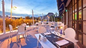 Disfrute de una cena en la terraza al aire libre con mesas y sillas blancas, que ofrece una impresionante vista del paisaje urbano, que recuerda a una noche de Escapada OD Ocean Drive con desayuno en Ibiza. - ForTwo - Planes para parejas