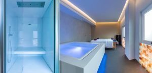 Disfrute de la relajación en la moderna sala de spa del Hotel SH Valencia Palace, con ducha de vapor, bañera iluminada y mesas de masaje bajo una relajante iluminación ambiental. - ForTwo - Planes para parejas